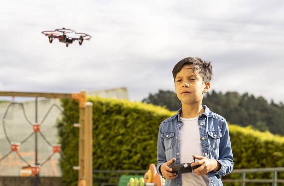 Young boy flying drone in open space