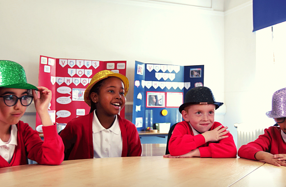 Children in school uniform wearing sparkly hats.