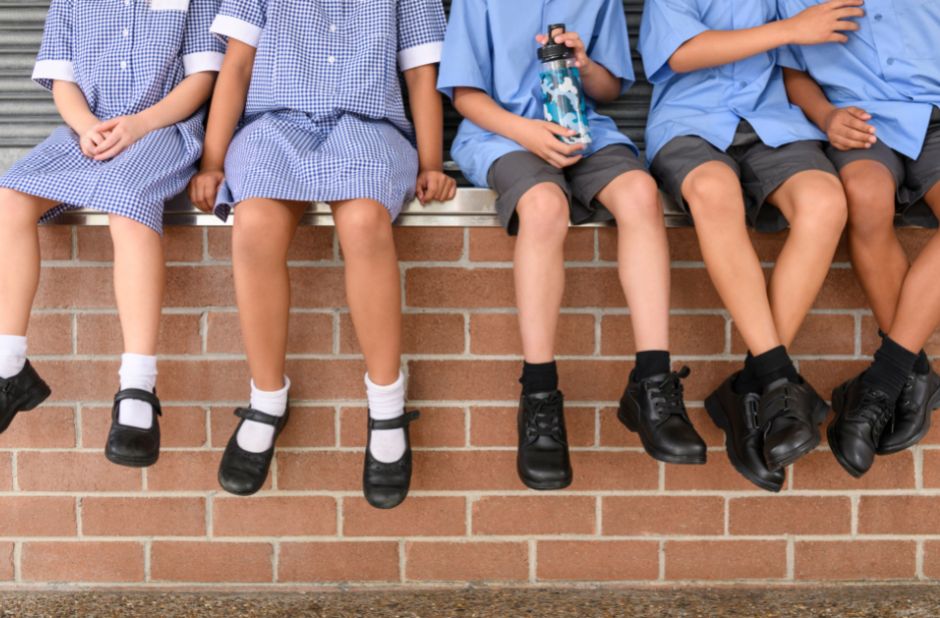 Children sat on wall in their school uniforms