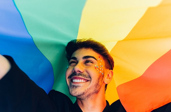 person smiling with rainbow flag
